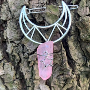 Detailed view of silver moon hair clip with pink crystal pendant on tree bark background