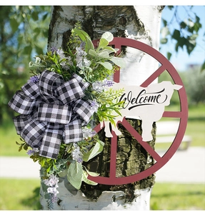 Close-up of Welcome wreath with cow silhouette and buffalo plaid bow on a tree