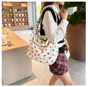 Detail of white corduroy shoulder bag with strawberry print and ruched strap details