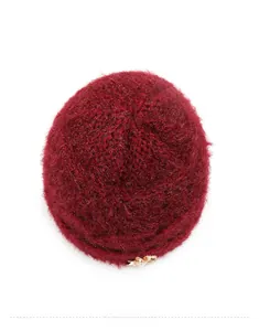 Detail of burgundy plush knit hat with golden flower pearl ornament and fluffy texture