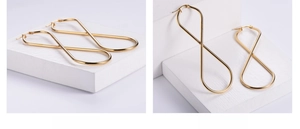 Detailed view of gold infinity figure-eight earrings on a white stone pedestal