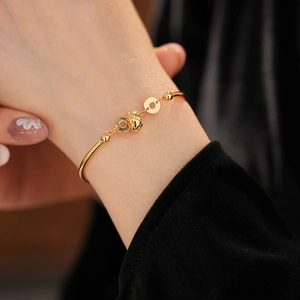 Detail of 18K gold-plated bangle with matelassé bead and zircon on black background