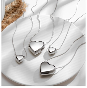 Macro detail of polished heart pendant necklaces on a white plate with creative shadows