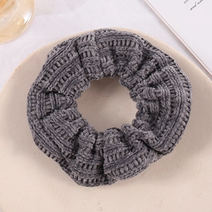 Detail showing grey knitted velvet scrunchie texture on a beige ceramic plate