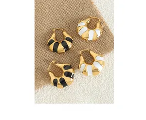 Detail of C-shaped hoop earrings featuring black and white enamel drip oil finish
