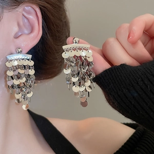 Detailed view of silver sequin tassel earrings with metallic cascading discs on a model