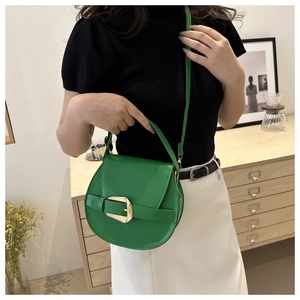 Fashionable green saddle bag with gold ring buckle worn by model in casual setting