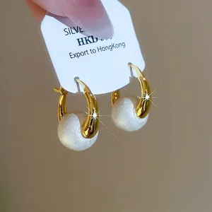 Elegant gold plated C-shaped earrings with large white pearl on display card