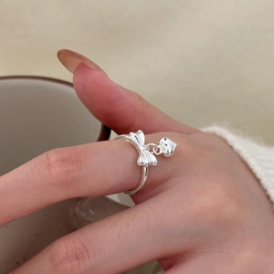 Detailed view of S925 silver bow ring with dangling heart pendant worn on index finger