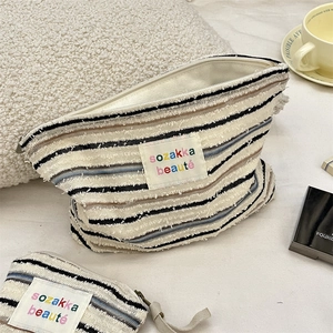 Detail of striped knit makeup bag set with metal zipper and sozakka beauté label