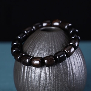 Detailed close-up of African Blackwood Buddhist beads bracelet on ceramic display stand