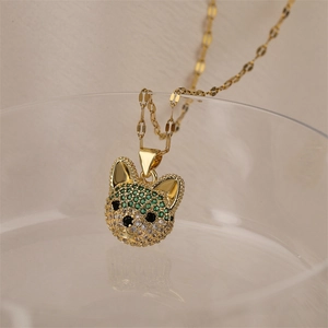 Close-up of gold dog pendant necklace with green and white crystals on glass edge