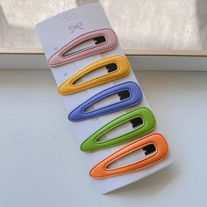 Detailed view of five colorful PU leather hair clips on a white display card set