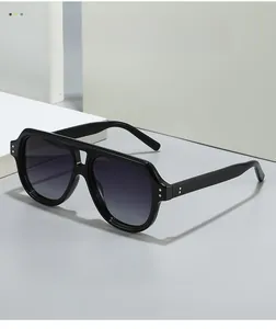 Detail of black aviator sunglasses with gold rivets and gradient lenses on a geometric base