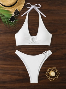 Dettagli del bikini bianco a coste con accessori a cuore dorati su sfondo di legno