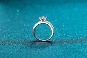 Detailed macro side view showing a four-prong round moissanite setting in silver