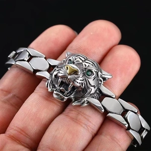 Macro view of a silver tiger head bracelet with gold accents and green eyes on metal links