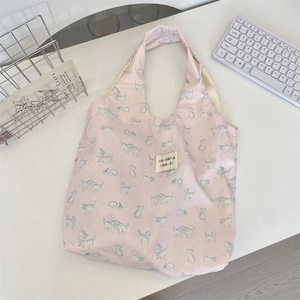 Close-up of pink fabric tote bag featuring blue cat floral prints and white woven label