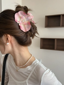Close-up of pink orchid hair claw with pearl detail and elegant matching jewelry set
