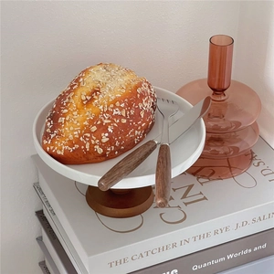 Ceramic cake stand with wood base and stainless steel flatware set in a lifestyle setting