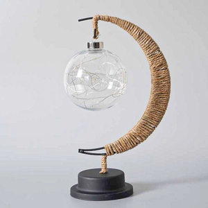 Macro detail of crescent moon LED lamp with twine wrapped iron and warm glass orb