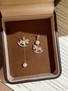 Detail of gold-plated horse earrings with micro-inlaid zircons and pearl tassels