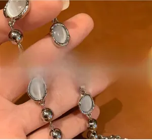 Close-up of polished silver beads and oval cat's eye stone necklace on leather background