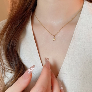 Dettaglio della collana con ciondolo a stella dorata e zircone sul collo