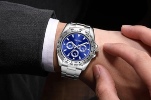 Detail of silver business watch with blue sunray dial worn with a charcoal formal suit