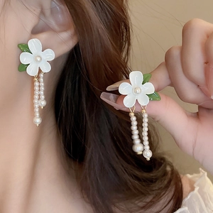 Detail of floral earrings with white petals green leaves and double row pearl tassels