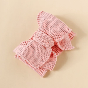 Close-up of a pink knitted baby headband with a large bow and soft yarn texture