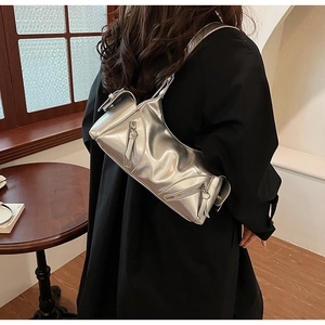Detail of silver metallic Y2K shoulder bag with pleated texture and buckle on model