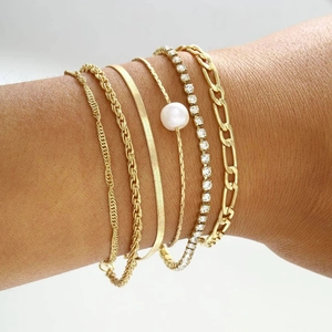 Close-up of five-piece gold bracelet set with pearls and crystals on wrist