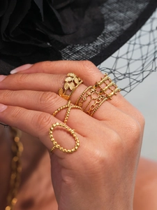 Detailed close-up of a stackable gold leaf and geometric ring set worn on a finger