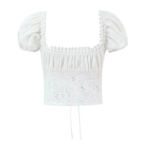 Détail du haut court en dentelle blanche avec manches bouffantes et encolure carrée