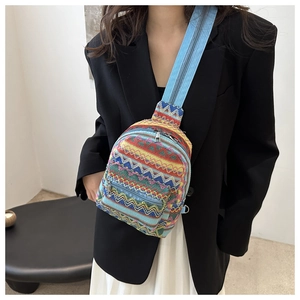 Close-up of bohemian embroidered chest bag with colorful geometric patterns and blue strap