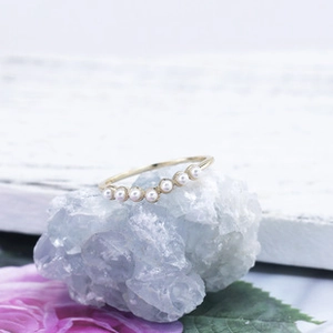 Dettaglio dell'anello a V dorato con perle bianche su base di cristallo azzurro