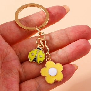 Pastoral ladybug and yellow flower keychain with gold metal ring on pink background