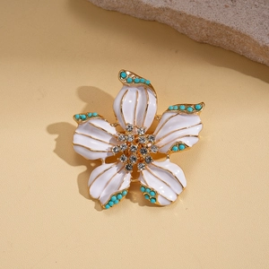 Detailed close-up of a floral brooch with white enamel petals and rhinestone center