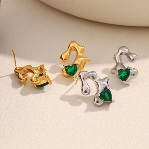 Close-up of irregular fluid metal heart earrings in gold and silver with green gems