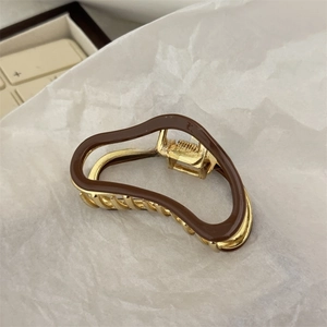 Detail of Korean style metal hair claw with brown wave acetate inlay and golden finish