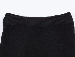 Gros plan sur le tissu tricoté noir montrant la texture fine et le détail du poignet côtelé