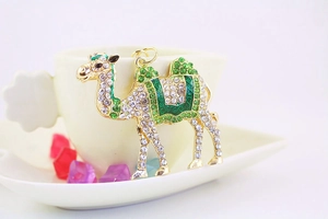 Detailed view of a golden rhinestone camel keychain with green enamel desert animal charm
