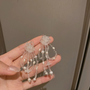 Detailansicht der weißen Perlenblumen-Ohrringe mit Quasten und Acrylperlen für Damen