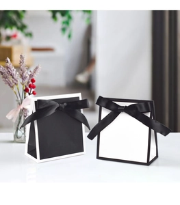 Détail de sacs cadeaux minimalistes avec nœuds en satin et fleurs séchées décoratives