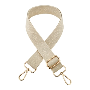 Detail of beige jacquard wide bag strap with gold metal hooks and geometric patterns