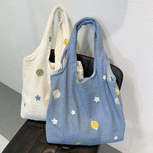Detail of cartoon star embroidery on soft off-white and blue fleece tote bags