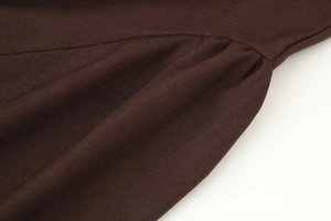 Detailed macro view of dark brown twill fabric with textured ruching on a short dress