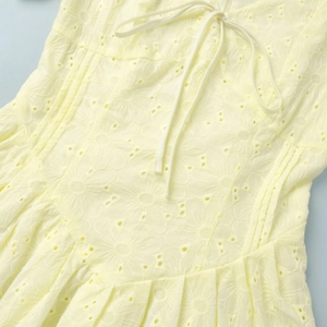 Detailed view of yellow cotton dress with floral embroidery and lace-up neckline