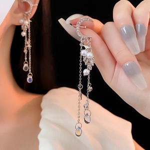 Detailed view of silver moon earrings with pearls and long tassel worn on ear